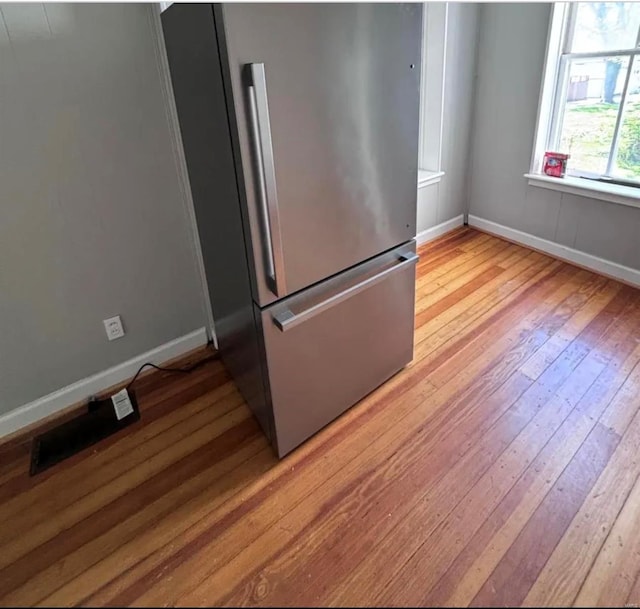 kitchen featuring light wood-type flooring, freestanding refrigerator, and baseboards