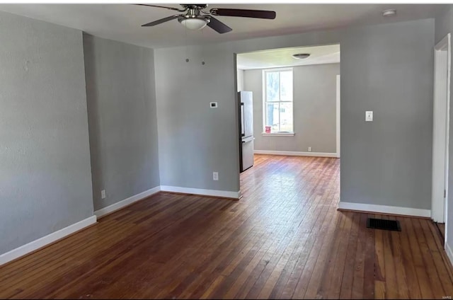 spare room with ceiling fan, wood-type flooring, visible vents, and baseboards