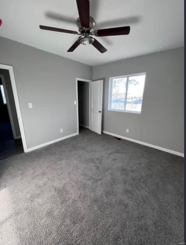 unfurnished bedroom featuring a ceiling fan, dark carpet, and baseboards