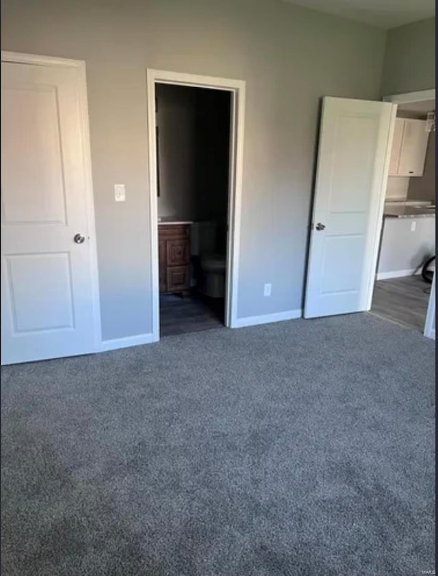 unfurnished bedroom featuring ensuite bath, carpet flooring, and baseboards