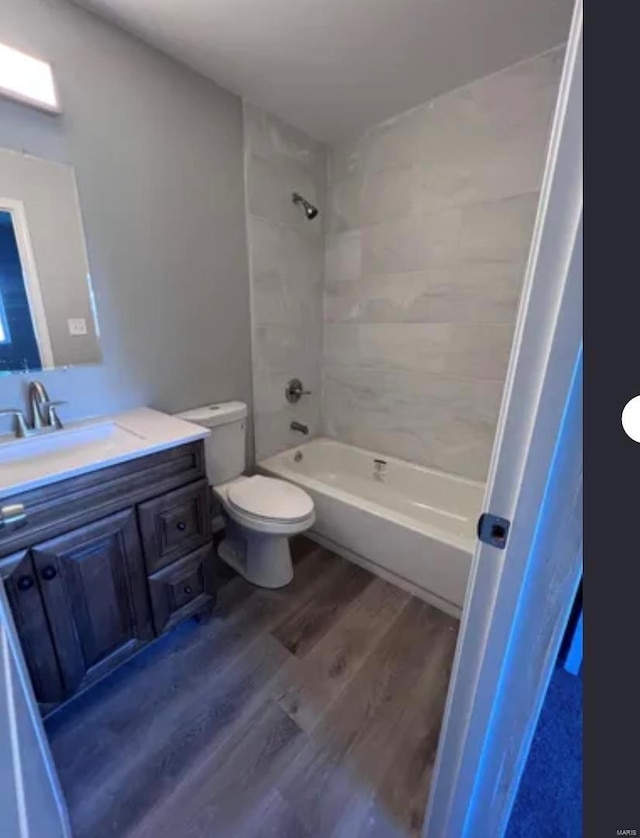 full bath featuring  shower combination, vanity, toilet, and wood finished floors