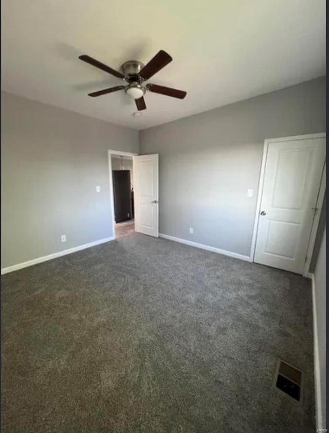 unfurnished bedroom with ceiling fan, dark colored carpet, visible vents, and baseboards