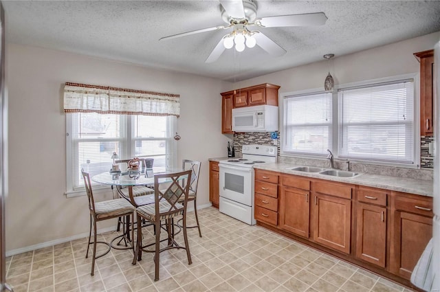 kitchen with white appliances, plenty of natural light, brown cabinets, and a sink