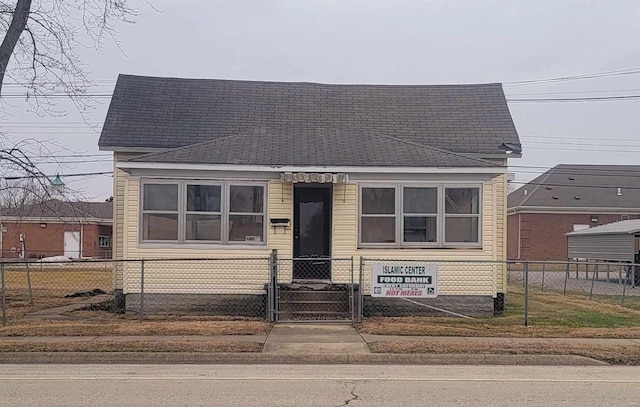 view of front of home featuring roof with shingles, a fenced front yard, and a gate