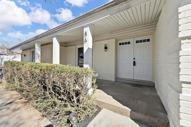 entrance to property with covered porch and brick siding