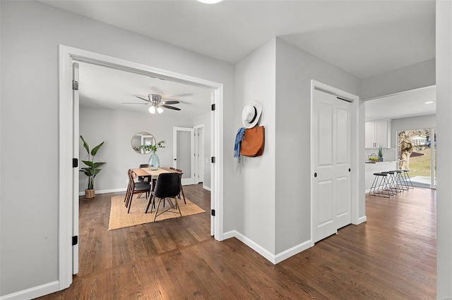 corridor with dark wood finished floors and baseboards