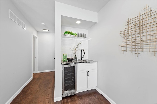 bar featuring baseboards, visible vents, wine cooler, dark wood-type flooring, and a sink