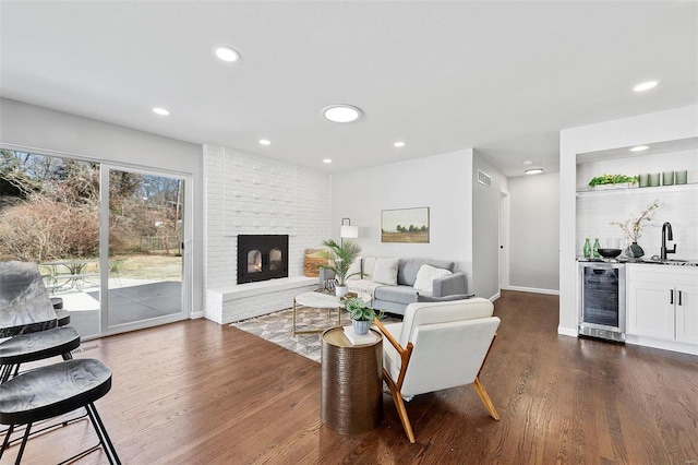 living room with wine cooler, recessed lighting, a fireplace, dark wood-style floors, and indoor wet bar