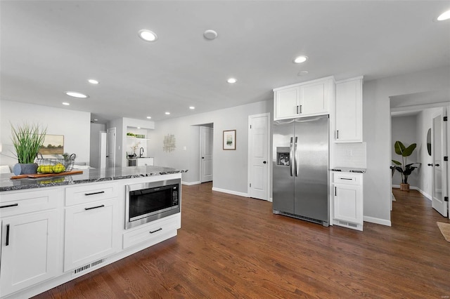 kitchen featuring dark wood-style flooring, dark stone countertops, stainless steel appliances, white cabinetry, and recessed lighting