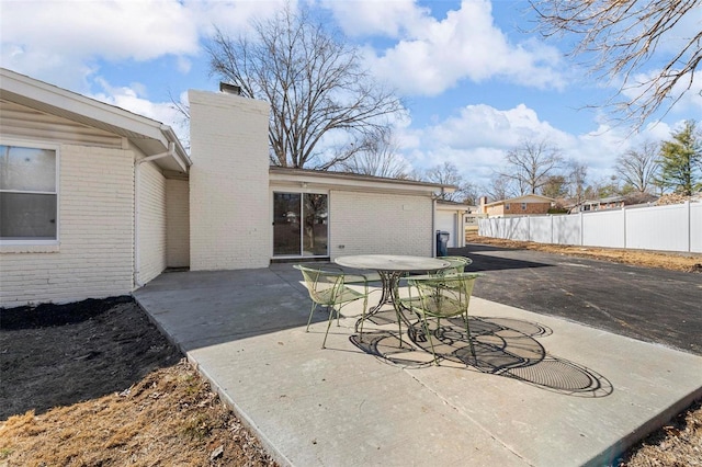 view of patio / terrace featuring a garage, fence, and aphalt driveway