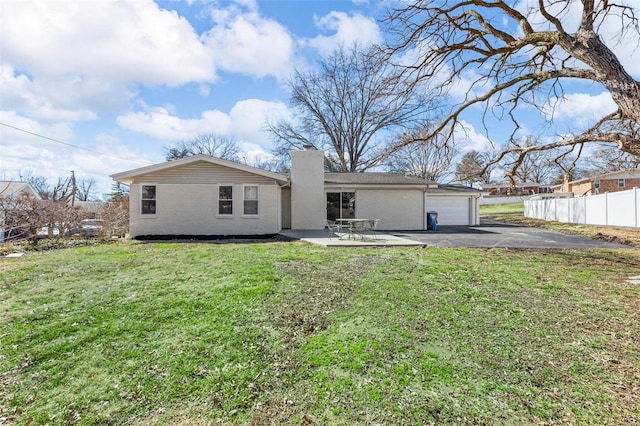 rear view of property featuring brick siding, fence, a lawn, a chimney, and a patio area