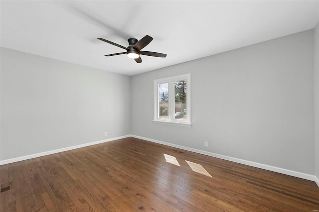 spare room featuring ceiling fan, dark wood finished floors, and baseboards