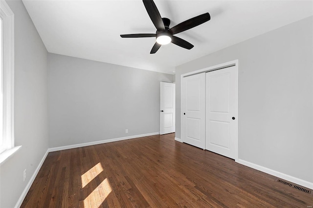 unfurnished bedroom with dark wood-style floors, a closet, and baseboards