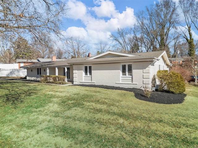 back of house with brick siding, fence, and a yard