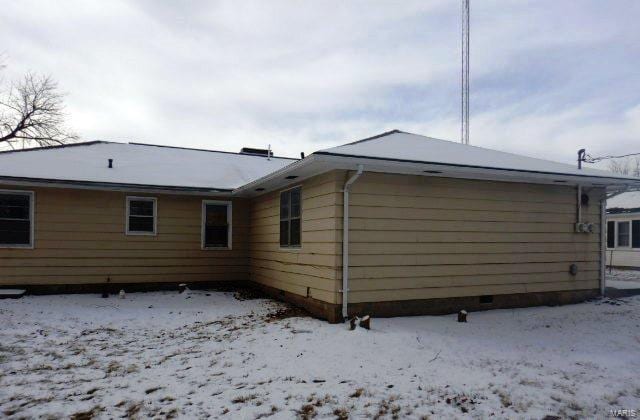 snow covered back of property featuring crawl space