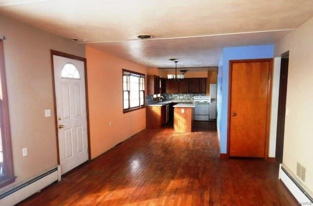 kitchen with a chandelier, a baseboard radiator, dark wood-type flooring, baseboard heating, and range