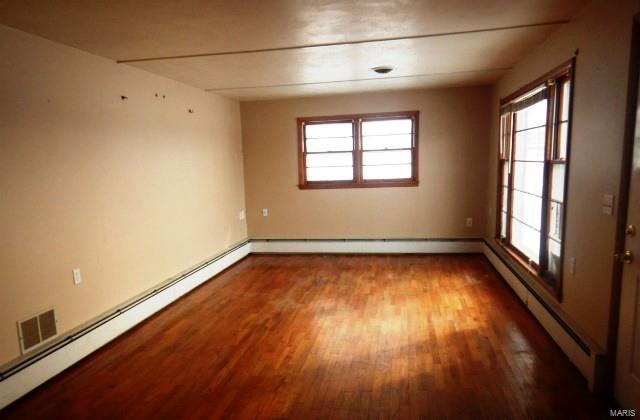 empty room featuring a baseboard heating unit and wood finished floors