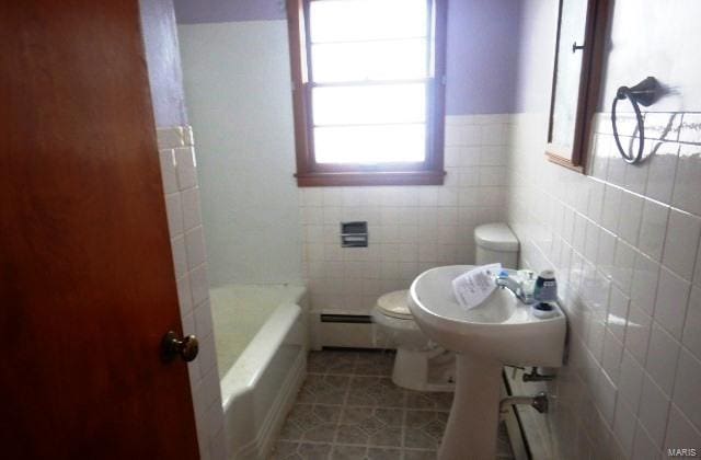 bathroom with toilet, a bathing tub, tile patterned floors, a baseboard heating unit, and tile walls