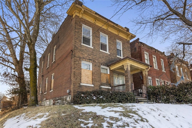 italianate house featuring covered porch and brick siding