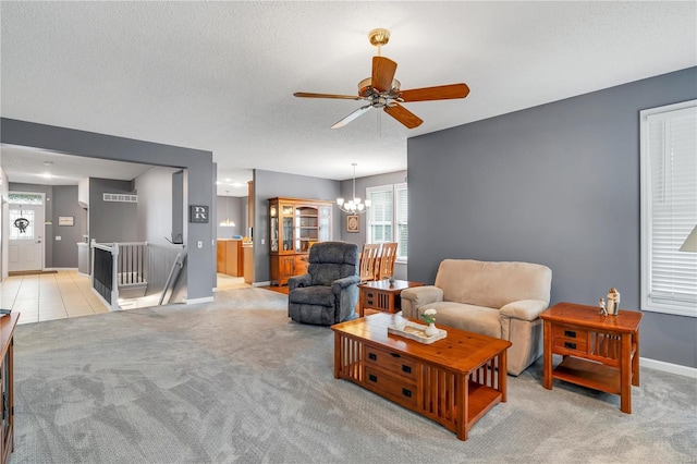 living area with a textured ceiling, ceiling fan with notable chandelier, baseboards, and light colored carpet