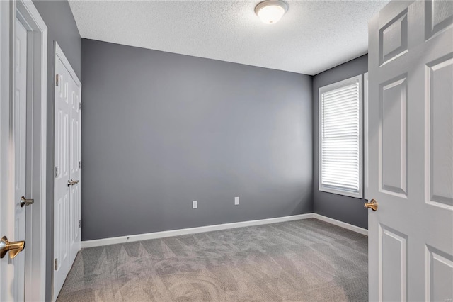 unfurnished bedroom featuring a textured ceiling, carpet, and baseboards