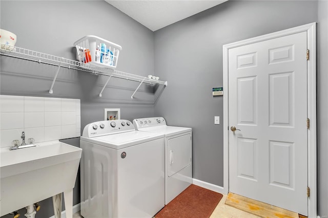 clothes washing area with washer and dryer, laundry area, a sink, and baseboards