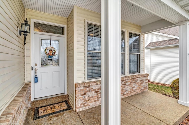 property entrance featuring a porch and brick siding