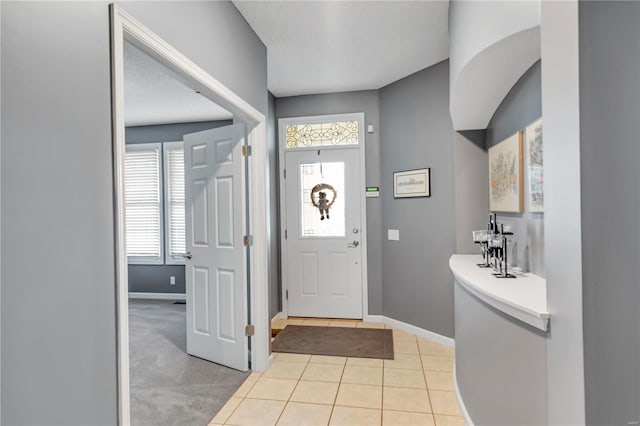 foyer with light tile patterned flooring, plenty of natural light, and baseboards