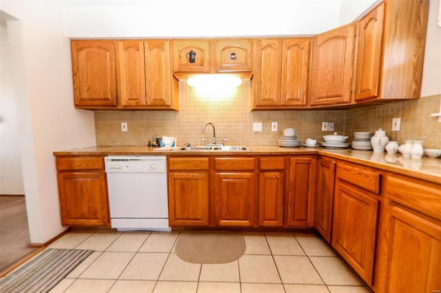 kitchen featuring light countertops, tasteful backsplash, white dishwasher, and a sink