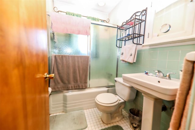 full bath featuring toilet, combined bath / shower with glass door, tile walls, and tile patterned floors