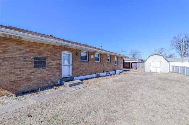 view of front of home with fence, a storage unit, an outbuilding, and brick siding