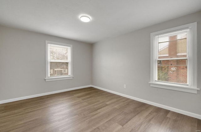 spare room featuring baseboards and wood finished floors