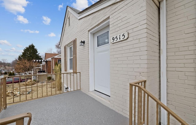 entrance to property with brick siding and a balcony