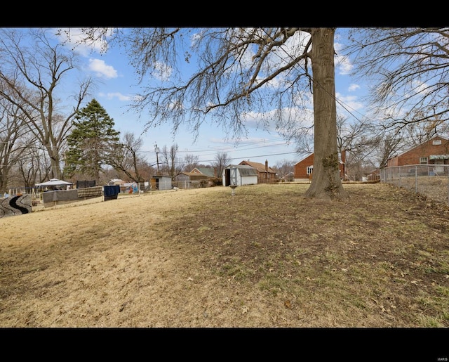 view of yard with a storage shed, fence, and an outbuilding