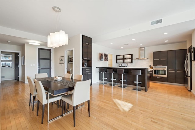 dining room featuring light wood finished floors, recessed lighting, visible vents, and baseboards