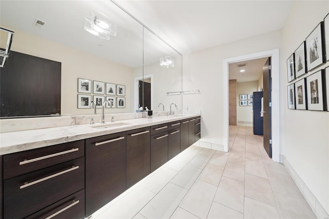 bathroom featuring double vanity, tile patterned flooring, baseboards, and a sink