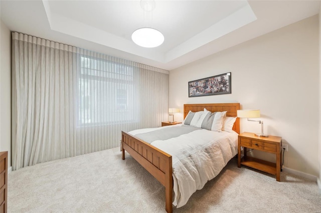 bedroom with light carpet and a tray ceiling