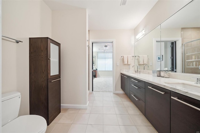 bathroom with toilet, double vanity, a sink, and tile patterned floors