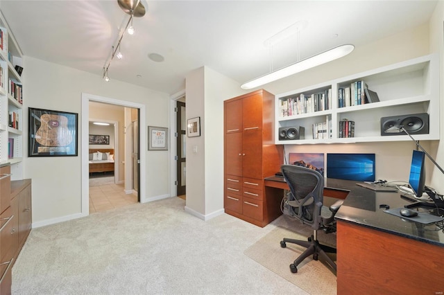 office with rail lighting, light carpet, and baseboards