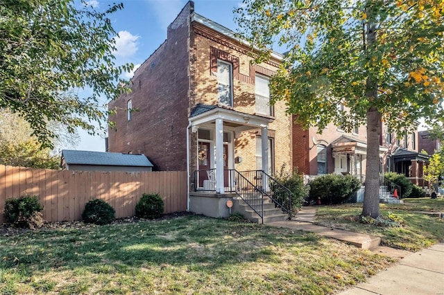 view of property featuring brick siding, a front yard, and fence