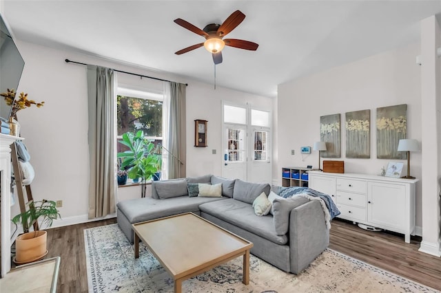 living area featuring wood finished floors, baseboards, and ceiling fan