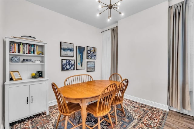 dining space with baseboards, a notable chandelier, and wood finished floors