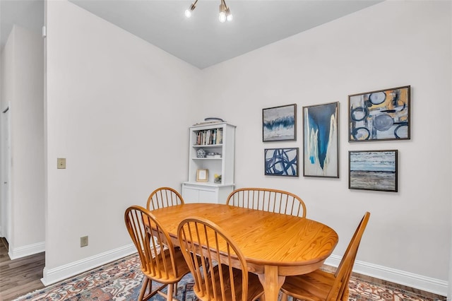 dining space with baseboards and wood finished floors