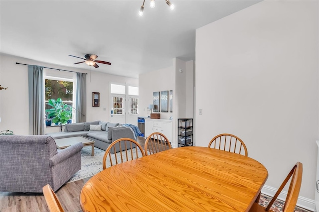 dining area with ceiling fan, baseboards, and light wood-style flooring