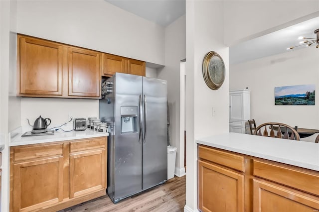 kitchen featuring brown cabinets, light wood-style floors, stainless steel fridge with ice dispenser, and light countertops