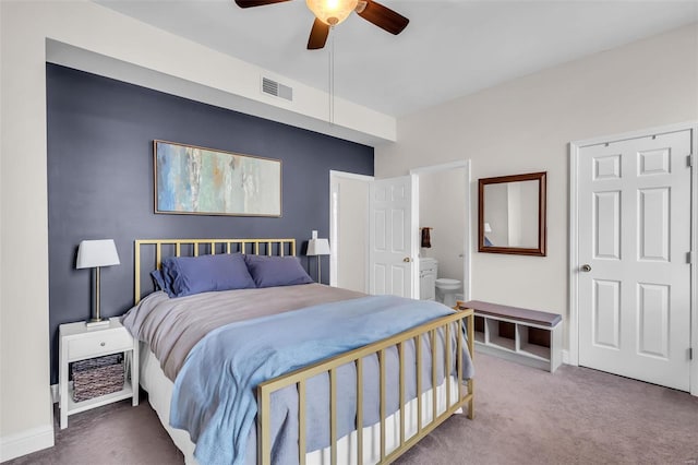 carpeted bedroom featuring baseboards, visible vents, ensuite bathroom, and ceiling fan