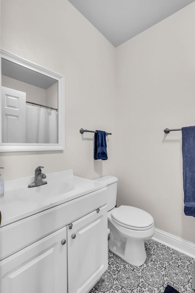 bathroom with tile patterned flooring, toilet, vanity, and baseboards