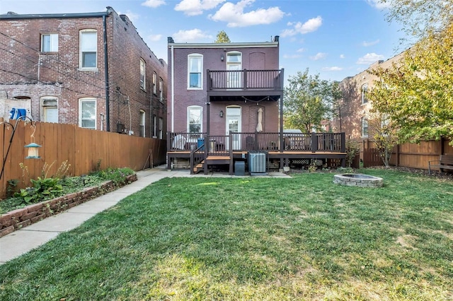 back of house featuring a wooden deck, an outdoor fire pit, central AC, a fenced backyard, and a yard