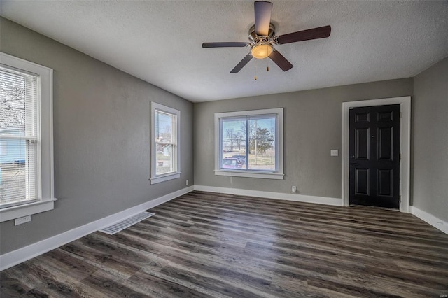 empty room with visible vents, ceiling fan, baseboards, dark wood finished floors, and a textured ceiling