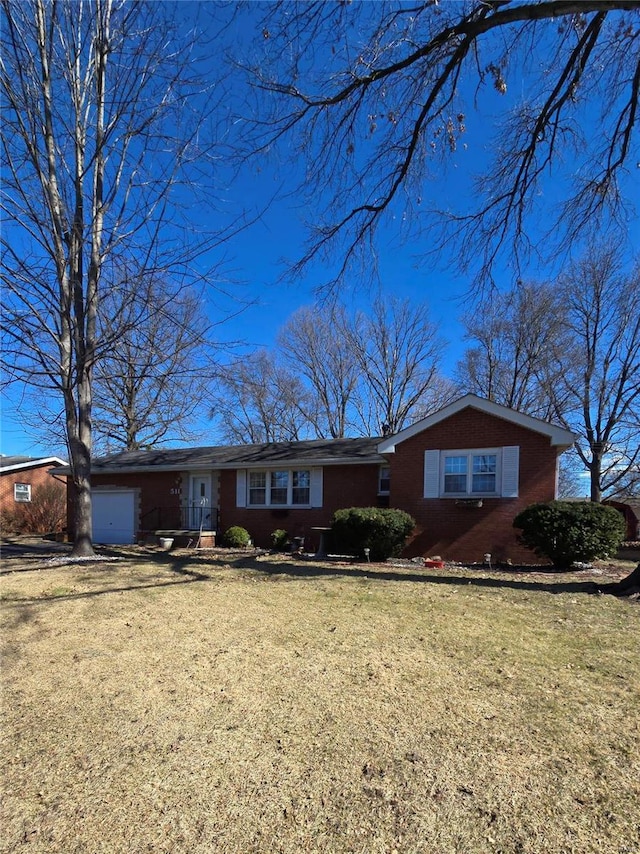 ranch-style house featuring an attached garage, driveway, brick siding, and a front yard